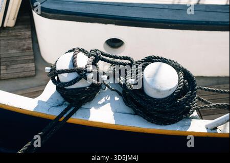 Primo piano di corde di ormeggio e dissuasori sul ponte di una nave con la scia Foto Stock