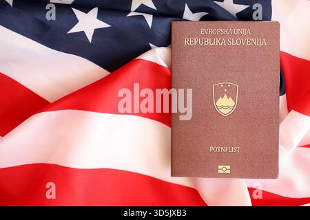 Passaporto sloveno sulla grande bandiera ondulata degli Stati Uniti d'America primo piano. Concetto di immigrazione e visto PER GLI STATI UNITI Foto Stock