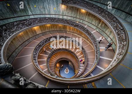 Vista dall'alto verso il basso della doppia scala a chiocciola Momo, con curve eleganti, motivi geometrici e simmetria nell'architettura moderna degli interni, Italia. Foto Stock
