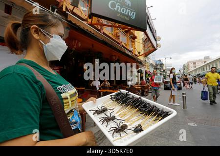 Bangkok, Thailandia - 22 luglio 2022: Una donna vende scorpioni e ragni come cibi esotici nell'iconica via Khaosan Road. Foto Stock