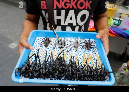 Bangkok, Thailandia - 22 luglio 2022: L'uomo vende scorpioni e ragni come cibi esotici nell'iconica via Khaosan Road. Foto Stock