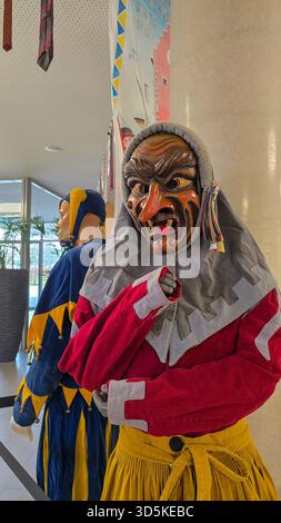 Meersburg, 27 febbraio 2025. Tradizionale maschera da strega in legno e costume giallo rosso per il Carnevale tedesco Fasnet, Fasnacht o Fasching. Foto Stock