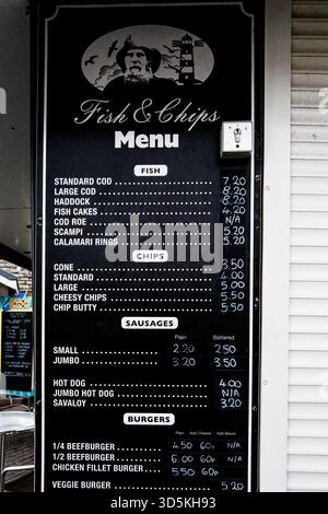 Menu di lavagna tradizionale con pesce e patatine fritte al Seaside Takeaway a West Bay, Bridport, Dorset. Foto Stock