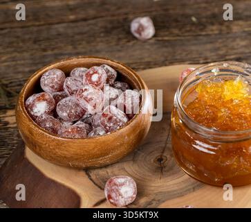 marmellata fatta di arance e agrumi ed essiccata in sciroppo di zucchero, frutta kumquat intera in polvere bianca, un vaso di vetro con marmellata d'arancia dolce è sul ta Foto Stock