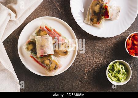 Involtini primaverili vegetariani con cetriolo, pepe e funghi fritti su un piatto con vista dall'alto Foto Stock