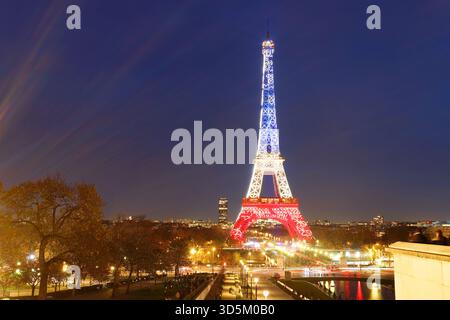 Pris, Francia - 12 novembre 2025 : la Torre Eiffel si illumina con i colori della bandiera nazionale francese - Blu, bianco e Rosso per onorare le vittime di nove Foto Stock