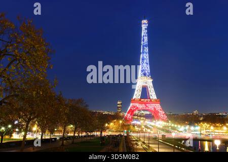 Pris, Francia - 12 novembre 2025 : la Torre Eiffel si illumina con i colori della bandiera nazionale francese - Blu, bianco e Rosso per onorare le vittime di nove Foto Stock