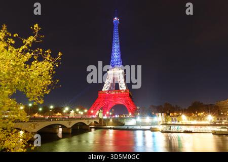 Pris, Francia - 12 novembre 2025 : la Torre Eiffel si illumina con i colori della bandiera nazionale francese - Blu, bianco e Rosso per onorare le vittime di nove Foto Stock