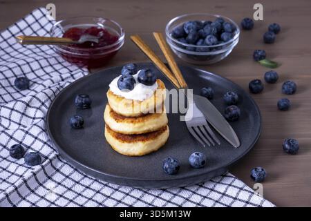 Frittelle di formaggio, frittelle di curdish, sciroppo con frutti di bosco freschi, marmellata, panna acida per colazione. Messa a fuoco selettiva Foto Stock
