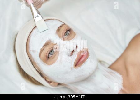 Donna caucasica adulta che riceve un trattamento viso ringiovanente presso una spa per la cura e il relax della pelle Foto Stock