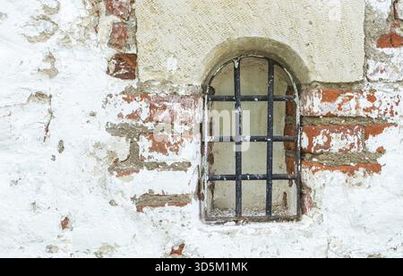 Frammento di un vecchio muro di mattoni rossi con una piccola finestra. Orientamento orizzontale, messa a fuoco selettiva Foto Stock