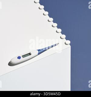 Concetto di medicina. Termometro medico. Cubo blu e bianco. Pillole influenzali. Integratore sanitario. Febbre malata. Aspirina. Laboratorio farmaceutico. Antibiot Foto Stock