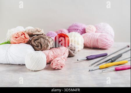 Su un tavolo ci sono tantissimi filati colorati, ganci all'uncinetto e aghi per maglieria Foto Stock