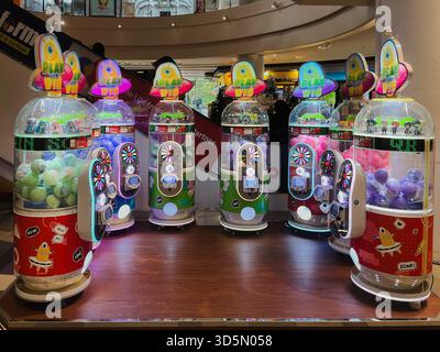 Balikpapan, Indonesia - 16 novembre 2025. Una fila di distributori automatici di artigli illuminati con temi alieni o UFO luminosi e capsule premio colorate o b Foto Stock