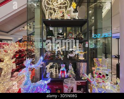 Balikpapan, Indonesia - 16 novembre 2025. Una vetrina di case in miniatura del villaggio natalizio, statue di renne illuminate e vari arredi per le vacanze Foto Stock