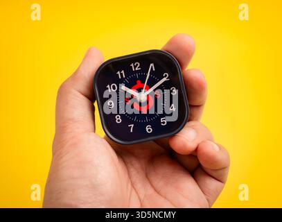 Mano con un piccolo orologio con il simbolo del dollaro rosso sulla faccia nera. Il concetto di tempo è denaro, efficienza aziendale, gestione del tempo, pianificazione finanziaria, d Foto Stock