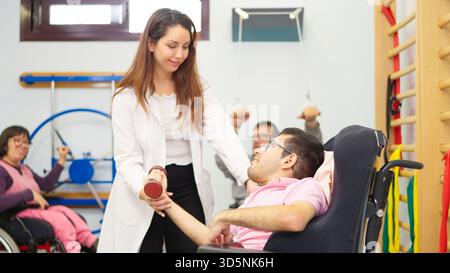 Fisioterapista che assiste l'uomo con disabilità fisica nell'esercizio riabilitativo Foto Stock