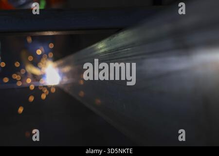 Vista ravvicinata del potente processo di saldatura industriale. Luce brillante e scintille calde che volano dal metallo fuso durante la fabbricazione dell'acciaio. scena focalizzata di Foto Stock