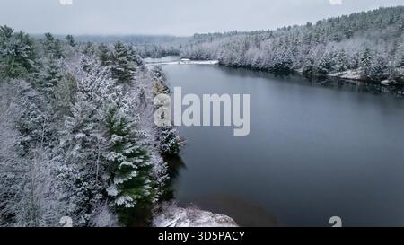 Vista aerea delle acque scure che riflettono il cielo coperto, contrastata da alberi carichi di neve nelle White Mountains, New Hampshire, Stati Uniti. Foto Stock