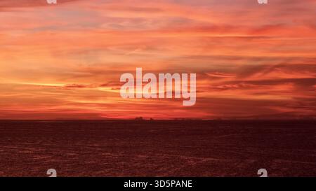 La vista aerea di un tramonto infuocato con sfumature color cremisi e oro dipinge il cielo sopra il tranquillo orizzonte di St. Pete Beach, Florida, Stati Uniti. Foto Stock
