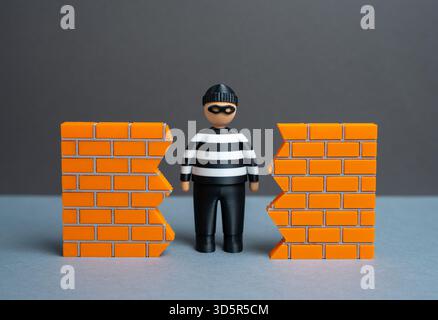 Un criminale trova un buco nel muro. Una violazione della sicurezza. La minaccia del furto di dati e della cybersicurezza. Vulnerabilità del sistema e accesso non autorizzato. H Foto Stock