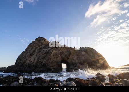 Onde oceaniche che si infrangono contro la formazione rocciosa di Keyhole Arch a Pfeiffer Beach, Big Sur, California. Foto Stock