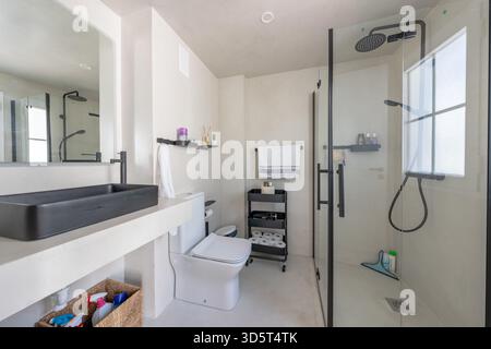 Bagno moderno con finiture nere e doccia in vetro nella casa mediterranea Foto Stock