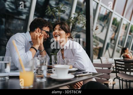 Coppia che si gusta un caffè mentre condivide un momento di gioia all'aperto Foto Stock