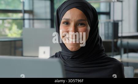 Felice positiva donna d'affari musulmana in hijab sorridente in ufficio araba etnica islamica imprenditrice donna lavoratrice ragazza sorridere toothy guardando la macchina fotografica Foto Stock