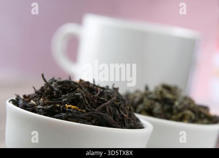 Tè nero e verde in ciotole bianche. Concentrati sul tè nero. Foto Stock