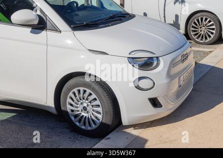 Auto elettrica bianca fiat 500e parcheggiata su una strada urbana, mostrando la parte anteriore e laterale Foto Stock