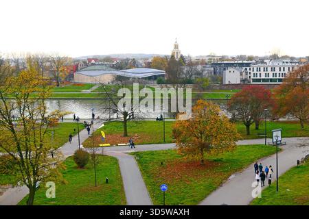 Paesaggio urbano autunnale con sentieri tortuosi nel parco e alberi colorati lungo un fiume, una giornata nuvolosa a Cracovia, Polonia Foto Stock