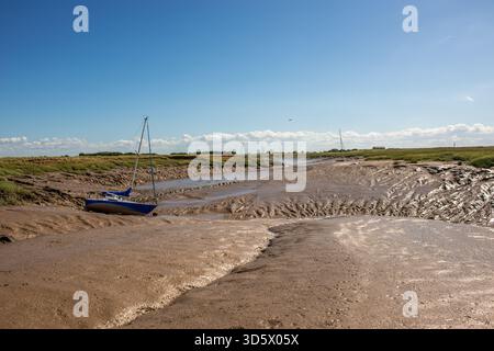 Barca bloccata nel fango secco nelle zone umide di marea del fiume Severn, canale di Bristol Foto Stock