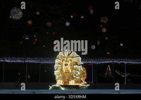 Decorazione illuminata della statua del leone dorato al mercato di Natale del Parco Városháza di notte a Budapest, Ungheria Foto Stock