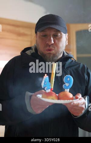Uomo che fa saltare le candele per la sua festa del 49esimo compleanno Foto Stock
