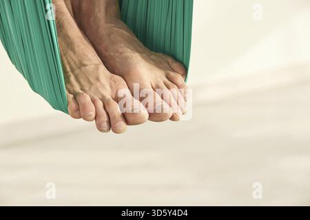 La persona maschile fa esercizio di lezioni di yoga sull'amaca. Meditazione in aria calma. Allenamento in studio per principianti Aero. Stile di vita degli uomini. Ragazzo che allena la posa zen. Verde. Amaca Foto Stock