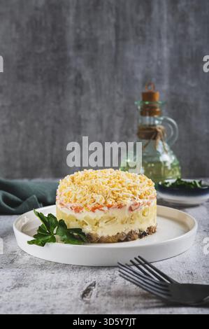 Tradizionale insalata a strati con pesce in scatola su un piatto sul tavolo vista verticale Foto Stock
