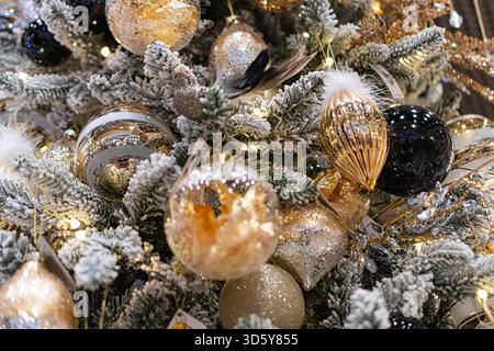 Vista ravvicinata di un albero di Natale decorato, realizzato in materiali artificiali con decorazioni bianche simili alla neve, con ornamenti sferici multicolore Foto Stock