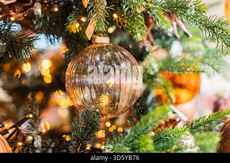 Vista ravvicinata di un albero di Natale decorato, su uno sfondo interno con dettagli architettonici ornamenti di varie forme e dimensioni sono appesi a fr Foto Stock