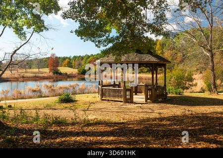 Un invitante gazebo si affaccia su uno stagno in una giornata di sole in autunno. Foto Stock