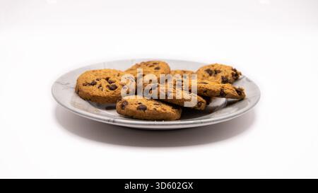 Biscotti con scaglie di cioccolato appena sfornati disposti su un piatto su uno sfondo bianco pulito. Dessert dolce o snack. Foto Stock