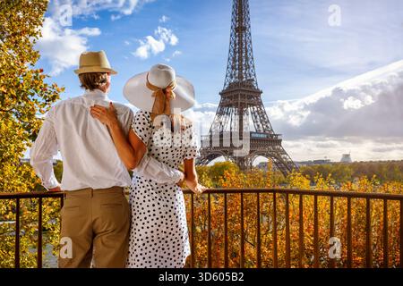 Romantico concetto di viaggio in città con un'elegante coppia di turisti che guarda la Torre Eiffel a Parigi, in Francia, dal loro balcone Foto Stock