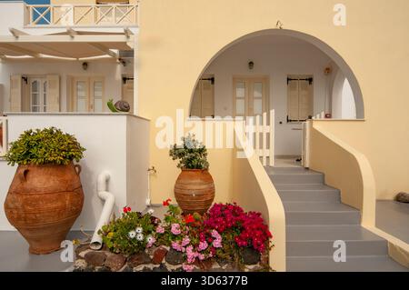 Ingresso con arco rustico, con vasi di terracotta e fiori vibranti a Santorini Foto Stock