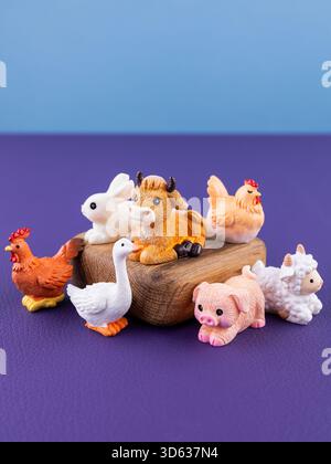 Primo piano di piccole e graziose statuine di animali domestici: oca, pollo, gallo, mucca, suinetto, coniglio, agnello, esposto su un podio di legno Foto Stock