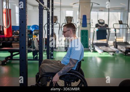 Uomo atleta in sedia a rotelle recupero dopo infortunio nel centro sportivo, preparazione per l'esercizio in palestra. Foto Stock