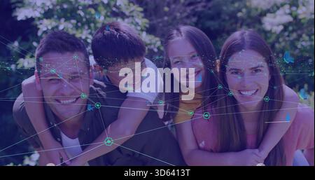 Posa di un gruppo di famiglie che trasportano i bambini in un giardino illuminato dal sole, con copertura in rete color ottanio e top colorati Foto Stock