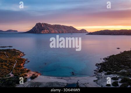Tramonto sereno sul mare blu calmo con isola, costa rocciosa, montagne lontane, orizzonte, Sardegna, Italia Foto Stock