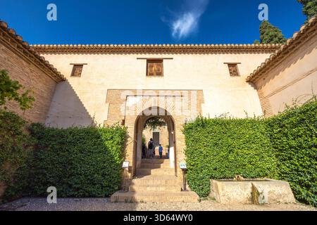 Granada, Spagna - 5 settembre 2024: Palazzo Generalife nel complesso dell'Alhambra. Antico ingresso ad arco in pietra a un cortile illuminato dal sole, incorniciato da lu Foto Stock