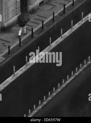Uomo con ombrello che cammina su una strada, dall'alto, monocromatico, scena stradale, Belgrado, Serbia Foto Stock