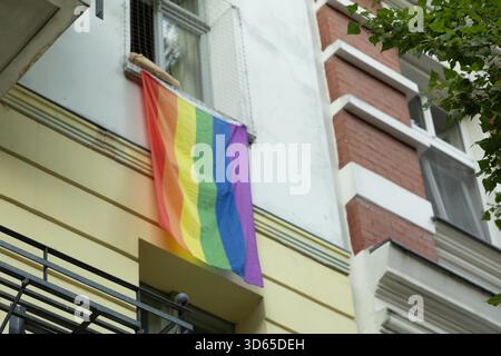 Berlino, Germania - 19 agosto 2025: La bandiera dell'Arcobaleno è esposta dalla finestra dell'edificio urbano della città. Foto Stock